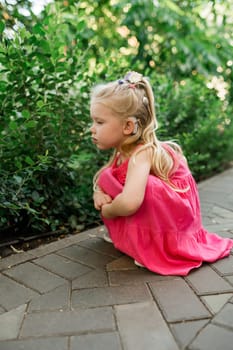 Child girl walks and have fun outdoor with cochlear implant on the head. Hearing aid and treatment concept. Copy space vertical.