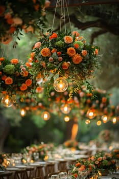 A table with a bunch of flowers hanging from the ceiling. The flowers are orange and green. The table is set for a dinner party