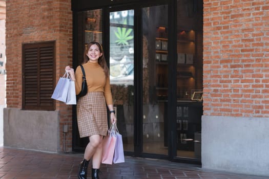 A woman is walking down a street with shopping bags in her hand.