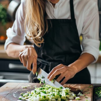 Unrecognizable close up shot of a beautiful chef woman with black apron chopping green cabbage.