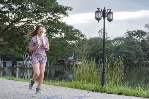 A woman is running in a park near a lake.