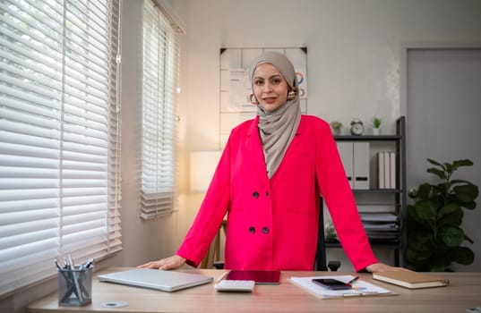 Confident Muslim businesswoman supervisor checks work on holiday and works in home office.