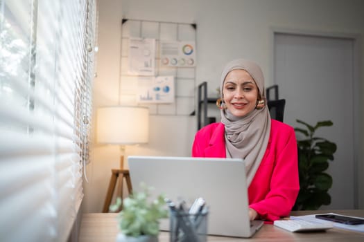 Confident Muslim businesswoman supervisor checks work on holiday and works in home office.