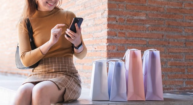 A woman sitting on a bench with a cell phone in her hand.