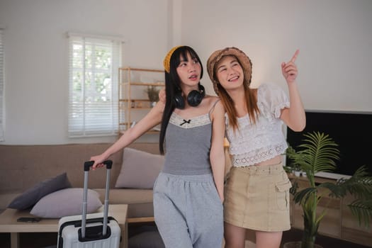 Two women are standing in a living room, one of them holding a suitcase.