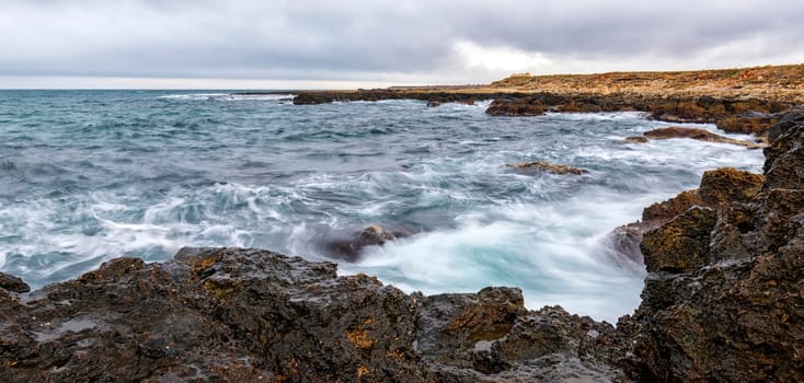 Stunning panoramic seascape with scenic clouds over the sea with rocky shore