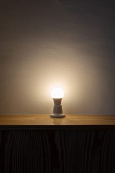 A Light Bulb On A Wooden Table.