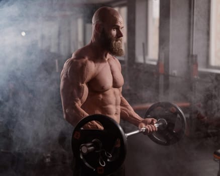 Caucasian bald topless man doing an exercise with a barbell in the gym. Bicep curls with weights