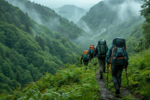 A group of four backpackers are hiking up a mountain trail. The trail is surrounded by lush green trees and the sky is cloudy. The backpackers are carrying backpacks and walking in a line