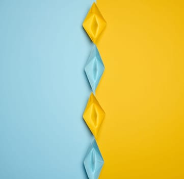 Paper boats on a yellow background, top view, representing the concept of unity and achieving common goals. Top view