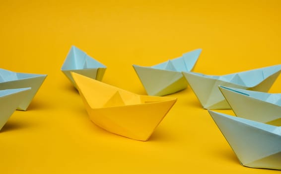 A group of blue paper boats surrounded one yellow boat, the concept of bullying, search for compromise. 