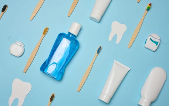 Mouthwash, toothpaste tube, dental floss on a blue background, oral hygiene.  Top view