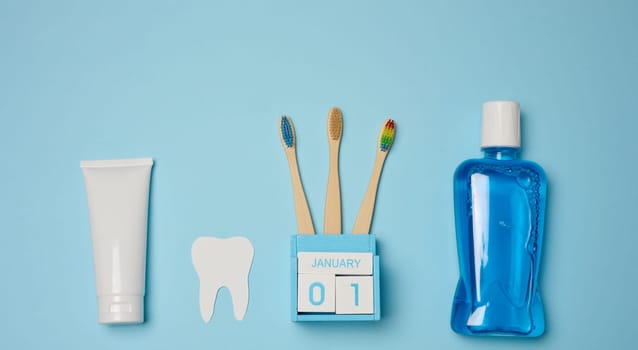 Mouthwash, toothpaste tube, dental floss on a blue background, oral hygiene. Top view