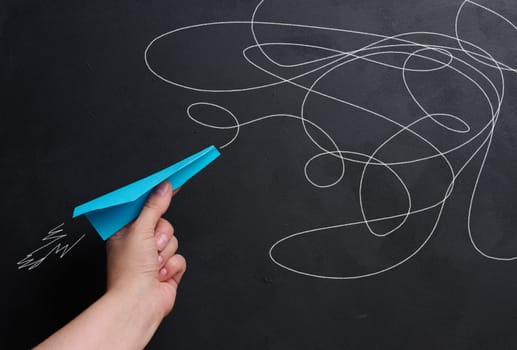 A hand holds a paper airplane with a drawn flight trajectory on the board, representing the concept of support and mentorship, providing assistance 