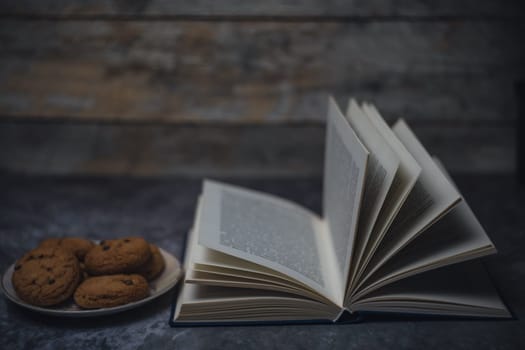 Open book next to a plate of cookies. High quality photo
