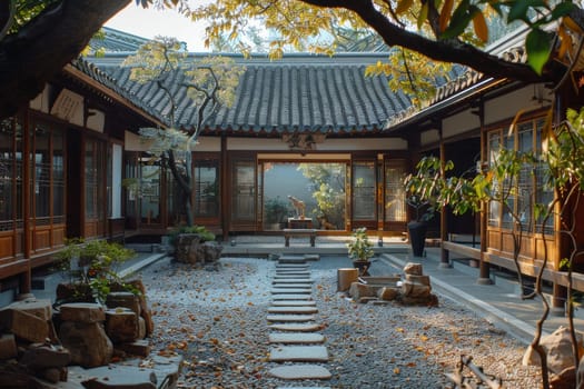 A courtyard with a stone path and a stone wall. The courtyard is surrounded by trees and has a Japanese style
