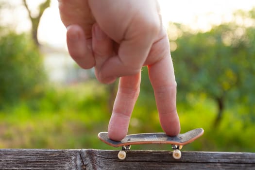 A man's fingers ride a small skateboard like a little man. High quality photo