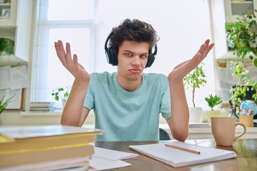 Webcam view of college student guy wearing headphones, talking looking at camera, sitting at desk in home. Young male studying online, video chat call conference, e-learning technology education