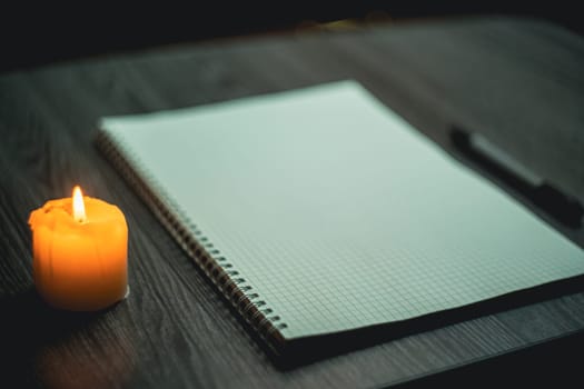 Large notebook and black marker in candlelight on the wooden table. High quality photo