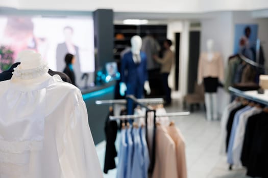 Formal apparel showcasing closeup in empty clothing store with blurred background. Stylish blouses and shirts on hanger and mannequin in shopping center with no people indoors