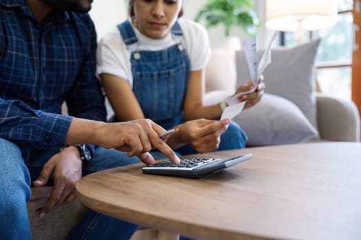 Indian married couple calculating bills, discussing planning budget together, serious wife and husband looking at calculator, checking finances.