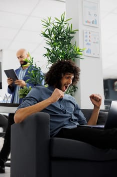 Excited start up company entrepreneur celebrating successful product launch. Happy young arab executive manager rejoicing effective marketing strategy while working on laptop in business office