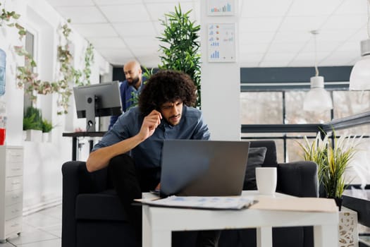 Project manager checking coworkers kpi on laptop in start up business office. Young arab entrepreneur thinking while solving complex problem on computer in corporate coworking space