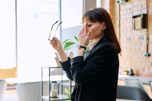 Tired sad mature business woman having stress headache, taking off glasses holding hand on face. Migraine, depression, illness, mental problems, difficulties