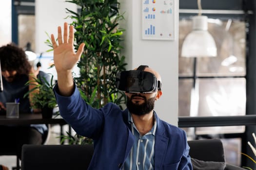Businessman in virtual reality headset working in start up business office. Company employee exploring metaverse and brainstorming in vr glasses in corporate coworking space