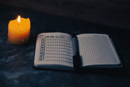 Darck photo of Notepad with a list of cases by candlelight. High quality photo