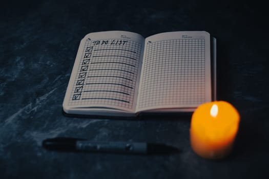 Darck photo of Notepad with a list of cases by candlelight. High quality photo