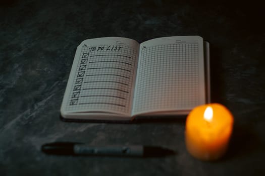 Darck photo of Notepad with a list of cases by candlelight. High quality photo