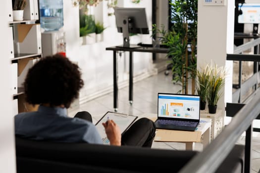 Arab businessman analyzing financial data on laptop screen in startup office. Executive manager comparing sales metrics and checking investment revenue statistics in coworking space