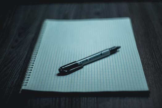 Large notebook and black marker in candlelight on the wooden table. High quality photo