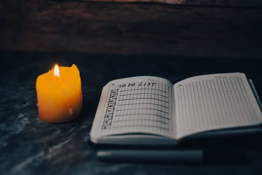 Darck photo of Notepad with a list of cases by candlelight. High quality photo