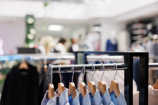 Male formal shirts hanging on metal rack in shopping center boutique. Stylish menswear brand from new collection showcasing for clients on hangers in clothing store with blurred background