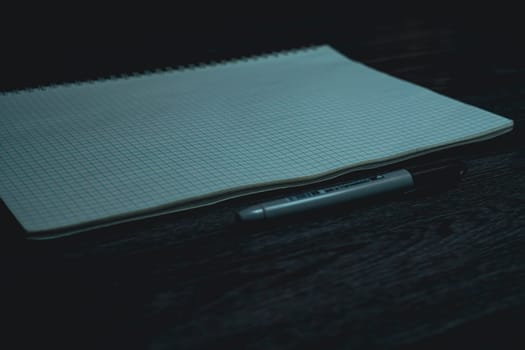 Large notebook and black marker in candlelight on the wooden table. High quality photo