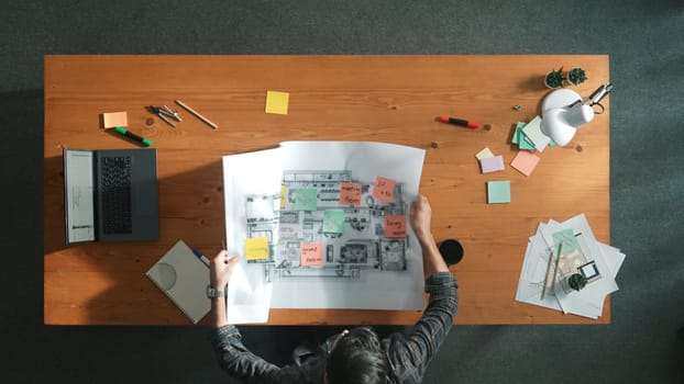 Top down view of skilled project manager hold project plan and open at meeting table. Aerial view of business people holding blueprint and thinking and planning about house construction. Symposium.