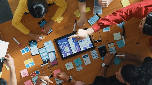 Top down view of business team writing idea on sticky note while planing for Ux Ui design for mobile phone interface. Group of creative designer working on wireframe prototype design. Convocation.