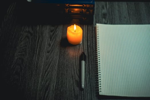 Large notebook and black marker in candlelight on the wooden table. High quality photo