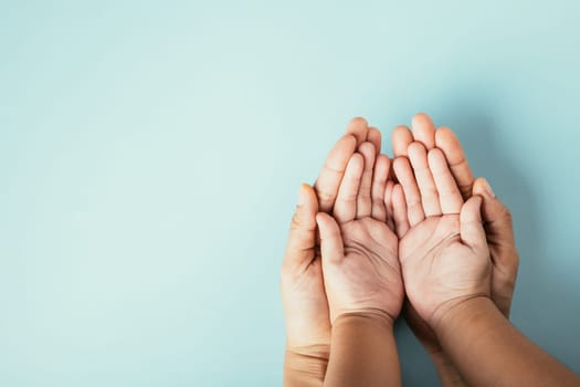 Top view studio shot of family hands stacked on an isolated background. Parents and child holding empty space symbolizing support on Family and Parents Day.