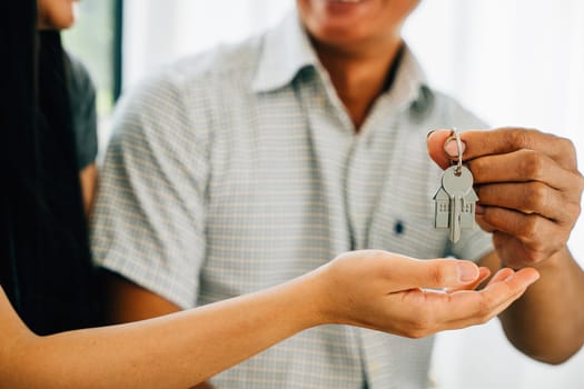 A smiling couple shows keys to their new house symbolizing happiness and success in homeownership. Reflecting joy achievement and the thrill of a significant investment.