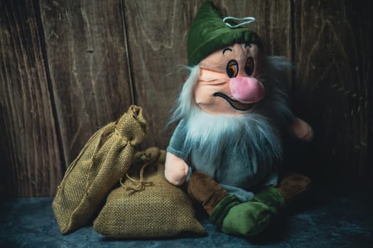 A toy gnome sits leaning on a wooden wall. High quality photo