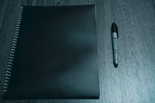 Large notebook and black marker in candlelight on the wooden table. High quality photo