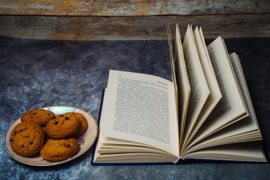 Open book next to a plate of cookies. High quality photo