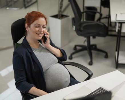 Pregnant woman using mobile phone in office