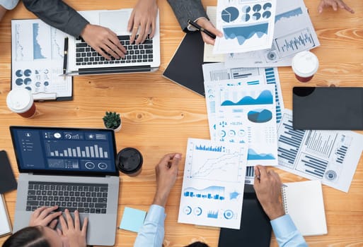 Multiracial analyst team use BI Fintech software to analyze financial data on meeting. Top view finance dashboard data display on laptop screen with analyzed chart for marketing indication. Concord