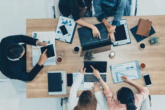 Top view of businessman executive in group meeting with other businessmen and businesswomen in modern office with laptop computer, coffee and document on table. People corporate business team uds