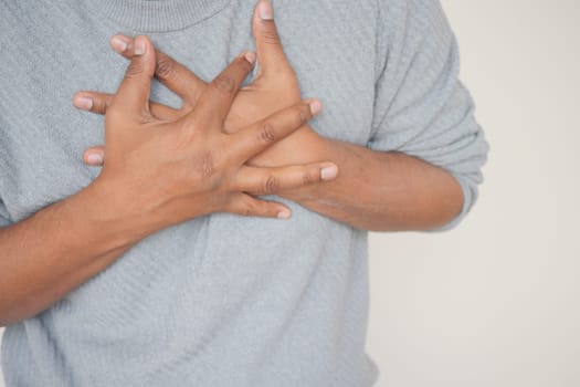 young man suffering pain in heart and holding chest with hand .