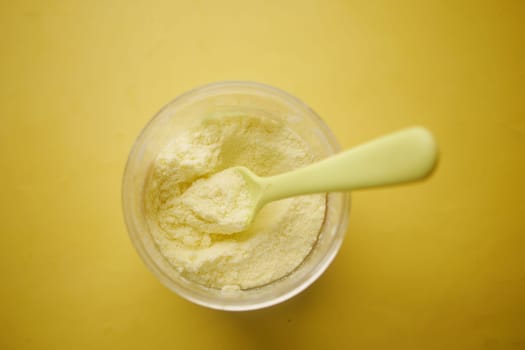 top view of baby milk powder and spoon on yellow background..